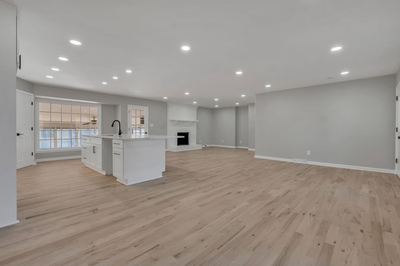 Open living area with hardwood floors, a white kitchen island, and a fireplace