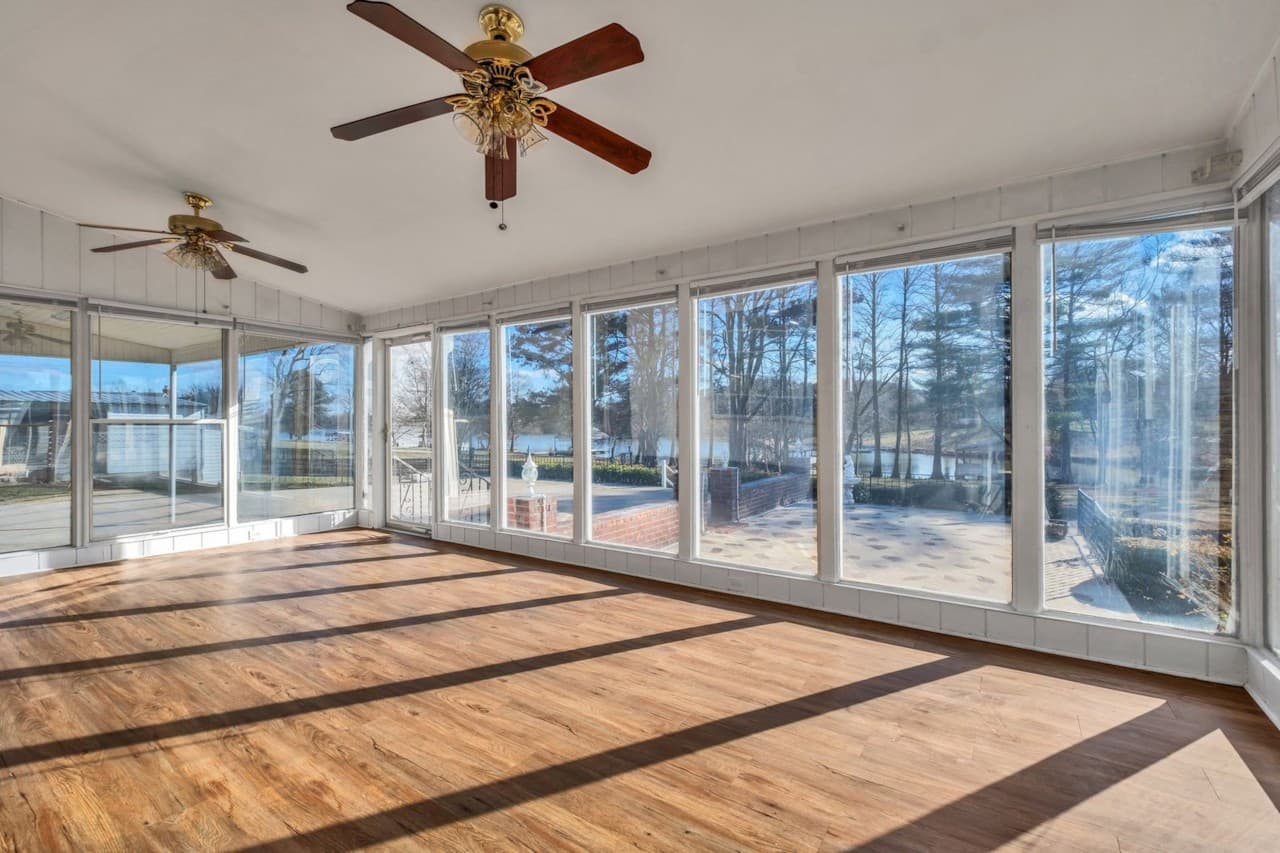 The Florida room with windows along the walls and sunlight across the floor